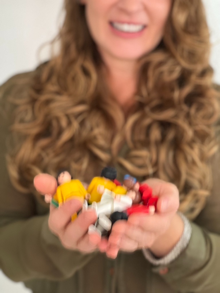 Mãos acolhendo bonecos de Constelação Sistêmica